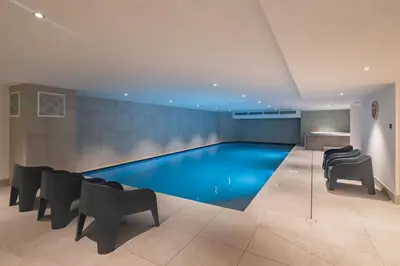 a swimming pool in a building with chairs and tables at Apartment Cumaru, Les Houches - by EMERALD STAY in Les Houches