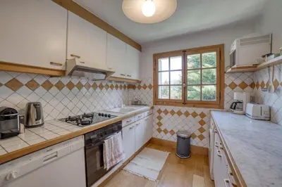 a kitchen with white cabinets and a stove top oven at Megève 4 seasons apartment in Megève