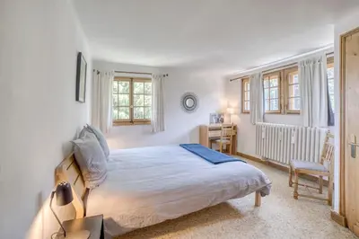 a bedroom with a bed and a desk and windows at Megève 4 seasons apartment in Megève