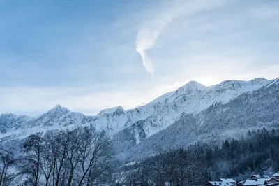 a snow covered mountain range with houses and trees at Apartment Camox, Les Houches - by EMERALD STAY in Les Houches