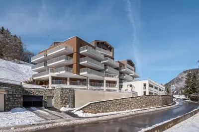a building in the snow next to a road at Apartment Camox, Les Houches - by EMERALD STAY in Les Houches