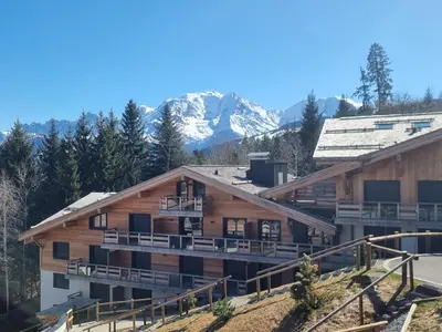 a large wooden building with mountains in the background at Appartement neuf 2 chambres près des pistes à Combloux avec parking - FR-1-560-158 in Combloux