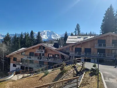 a resort building with a pool and mountains in the background at Appartement neuf 2 chambres près des pistes à Combloux avec parking - FR-1-560-158 in Combloux