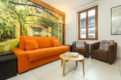 a living room with an orange couch and two chairs at Apartment Maisonnee - A Charming Chamonix Haven in Chamonix-Mont-Blanc