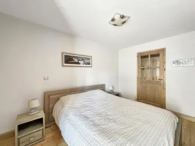 a white bedroom with a bed and a wooden cabinet at ROUS02 Appartement 6 8 personnes au centre station in Les Carroz d'Araches