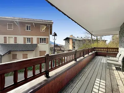 a balcony with a wooden deck and a building at ROUS02 Appartement 6 8 personnes au centre station in Les Carroz d'Araches