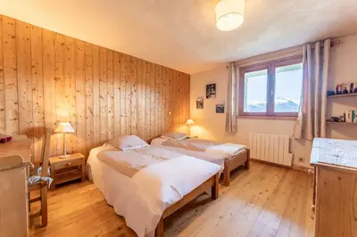 two beds in a room with wooden walls at Chalet Sapi in Combloux