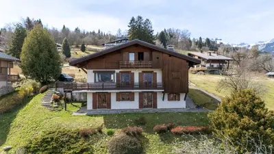 a large house on a hill with a yard at Chalet Sapi in Combloux