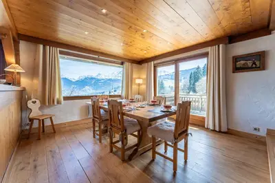 a dining room with a table and chairs and large windows at Chalet Sapi in Combloux
