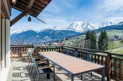 a balcony with a table and chairs and mountains at Chalet Sapi in Combloux