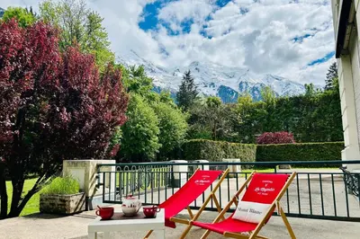 two red chairs on a porch with mountains in the background at Magnificent duplex in a former Palace in Chamonix-Mont-Blanc