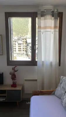 a bedroom with a bed and a large window at Le studio du Cerf in Chamonix-Mont-Blanc