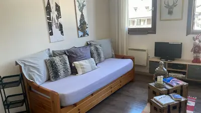 a bedroom with a bed with pillows and a tv at Le studio du Cerf in Chamonix-Mont-Blanc