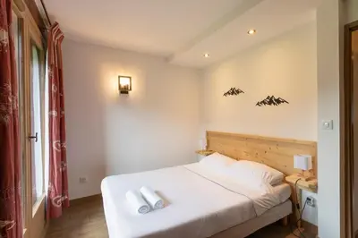 a bedroom with a bed with two white towels on it at Cabana & Alp'évasion - Pools, Sauna, Pool Table in Samoëns