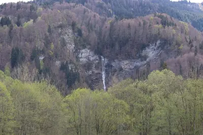 a waterfall on the side of a mountain with trees at Cabana & Alp'évasion - Pools, Sauna, Pool Table in Samoëns