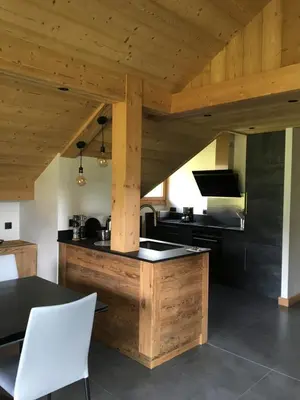 a kitchen with a wooden ceiling and a table and chairs at Les Séracs in Combloux