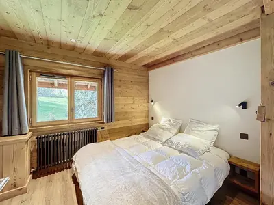 a bedroom with a large bed in a room with wooden walls at Les Séracs in Combloux