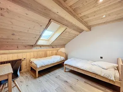 a bedroom with two beds and a table and a window at Les Séracs in Combloux