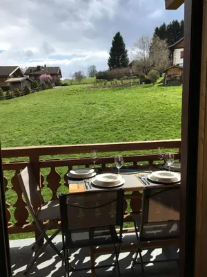 a table and chairs on a balcony with a view of a field at Les Séracs in Combloux