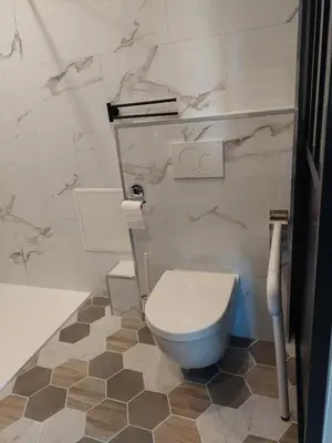 a white toilet in a bathroom with marble walls at Appartement adapté PMR 4 personnes Saint Gervais les Bains in Saint-Gervais-les-Bains