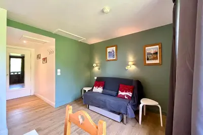 a living room with a blue couch and green walls at Petite Cordée in Combloux