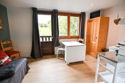a living room with a bed and a desk and a window at Petite Cordée in Combloux