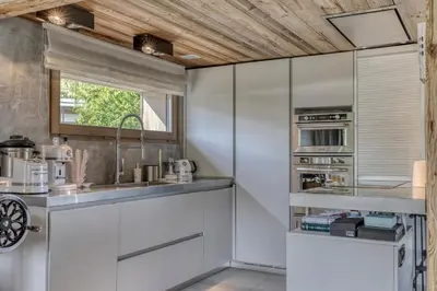 a kitchen with white cabinets and a window at Chalet de luxe proche du village de Megève in Megève