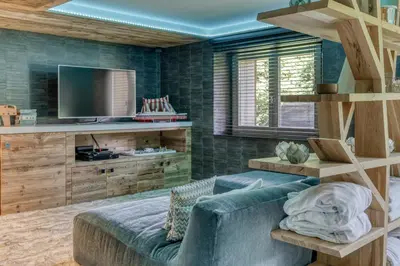 a living room with a couch and a tv at Chalet de luxe proche du village de Megève in Megève