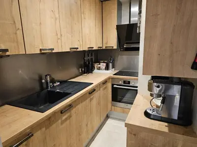 a kitchen with wooden cabinets and a black sink at Rouge-Gorge, Appartement de charme, 3 chambres, Megève - Rochebrune in Megève