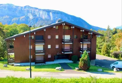 a large brown building with a mountain in the background at Studio Carroz d'Arâches 4 pers in Arâches-la-Frasse