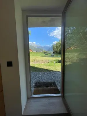 a door with a view of a field through a window at Cozy & modern apartment in Samoëns