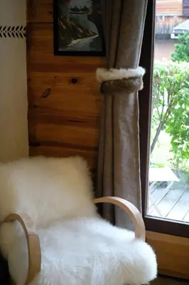 a white furry chair in front of a window at Cosy alpine apartment with pool and stunning views in Saint-Gervais-les-Bains
