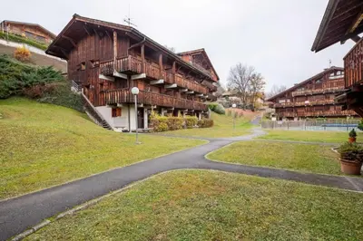 a winding road in front of a wooden building at Cosy alpine apartment with pool and stunning views in Saint-Gervais-les-Bains