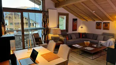 a living room with a couch and a table with a laptop at Luxury Penthouse With Mont Blanc Views In Megève in Megève