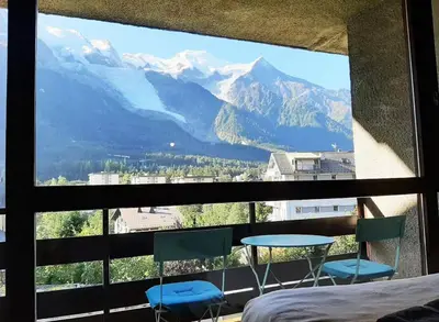 a bedroom with a view of mountains from a window at Grand Studio 25 m2, lumineux, central, vue Mont-Blanc in Chamonix-Mont-Blanc