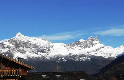 a snow covered mountain in front of a house at Duplex Saint Gervais in Saint-Gervais-les-Bains