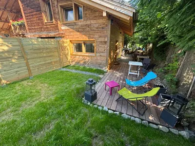 a backyard with a deck with chairs and a table at Face au MtBlanc avec jardin in Les Houches
