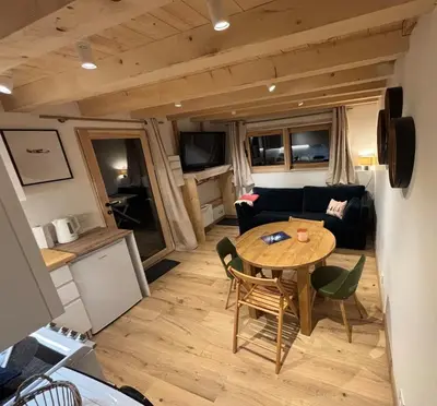 a living room with a table and chairs and a couch at Face au MtBlanc avec jardin in Les Houches