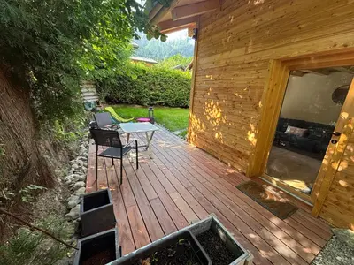 a wooden deck with a table and chairs on it at Face au MtBlanc avec jardin in Les Houches