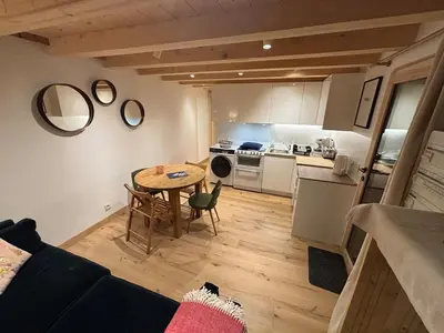 a living room with a table and a kitchen at Face au MtBlanc avec jardin in Les Houches
