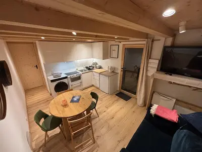 a living room with a table and a kitchen at Face au MtBlanc avec jardin in Les Houches