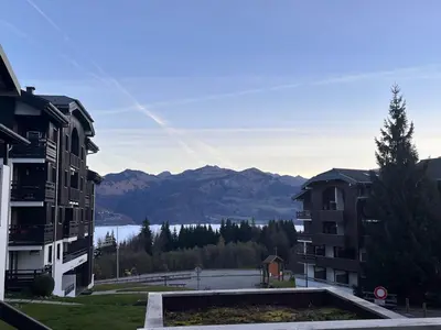 a view of a lake and mountains with buildings at Le LODGE Les Esserts 1100 Morillon in Morillon