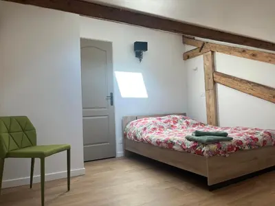 a bedroom with a bed and a green chair at Ambiance alpine in Sallanches