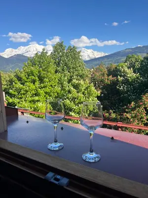 two wine glasses sitting on a table on a balcony at Ambiance alpine in Sallanches