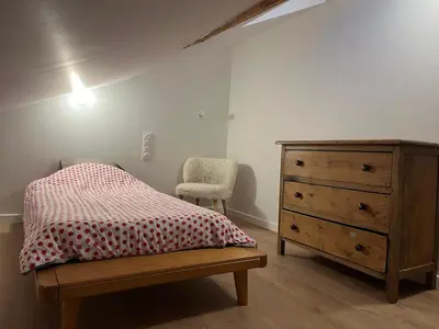 a bedroom with a bed and a dresser and a chair at Ambiance alpine in Sallanches