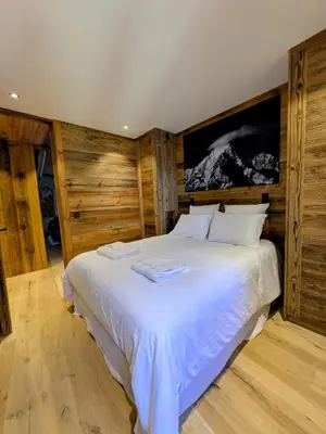 a bedroom with a large white bed with wooden walls at Appartement Nuage, Luxe, centre village Megève in Megève