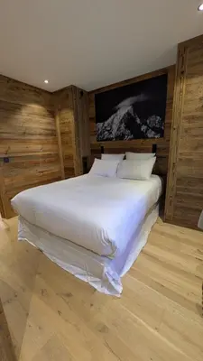 a large white bed in a room with wooden walls at Appartement Nuage, Luxe, centre village Megève in Megève