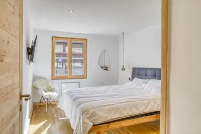 a bedroom with a large bed and a chair at Huxa Appt Megève Centre in Megève
