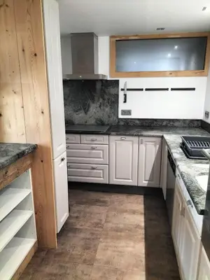 a kitchen with white cabinets and marble counter tops at Chalet Peppa in Sallanches