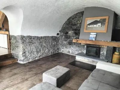 a living room with a fireplace and a stone wall at Chalet Peppa in Sallanches